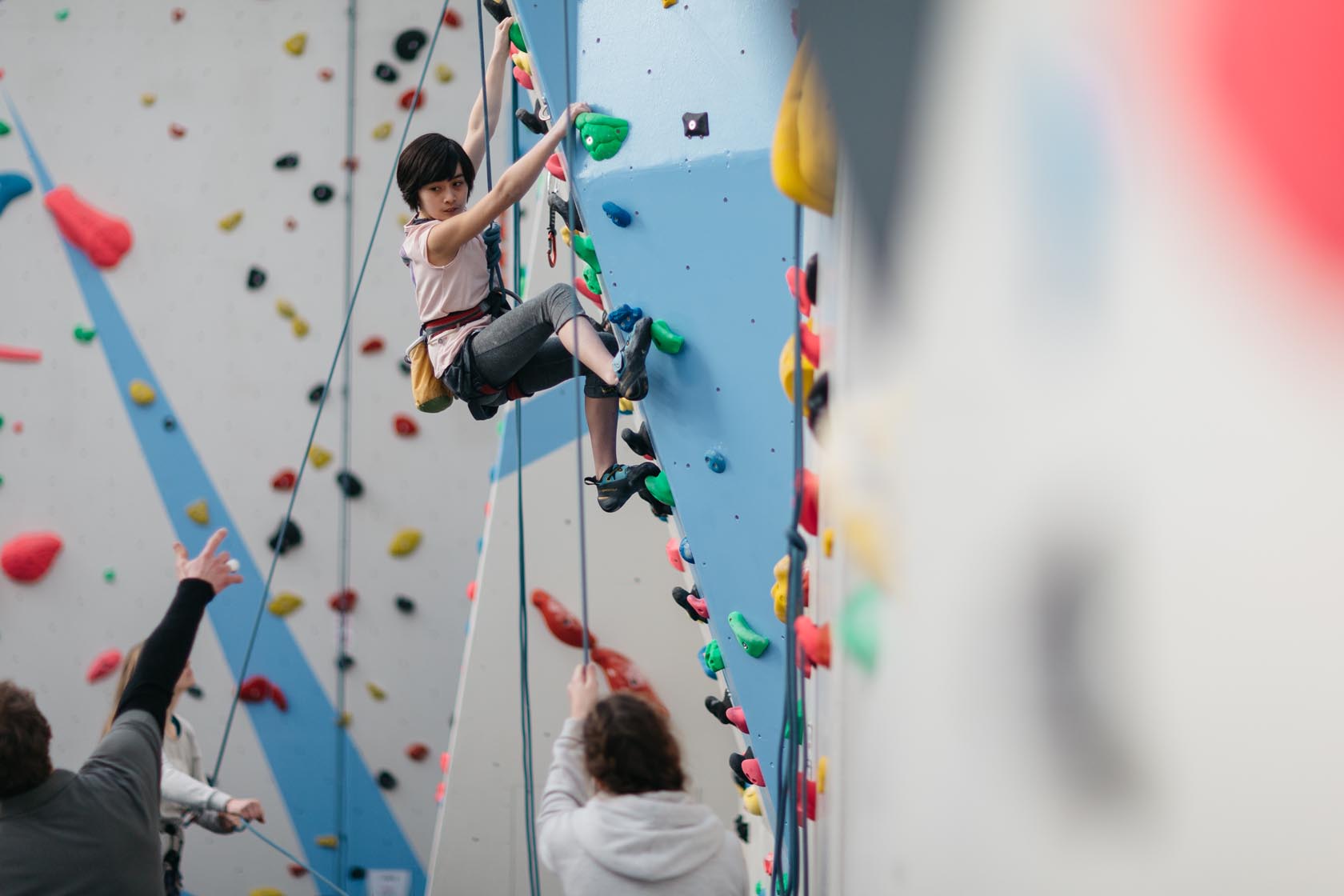 Child wearing climbing harness hanging on wall